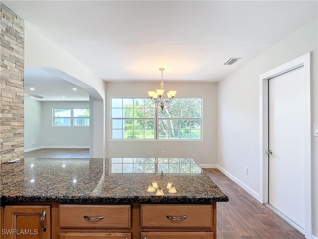 kitchen featuring dark stone counters, pendant lighting, a chandelier, and hardwood / wood-style floors