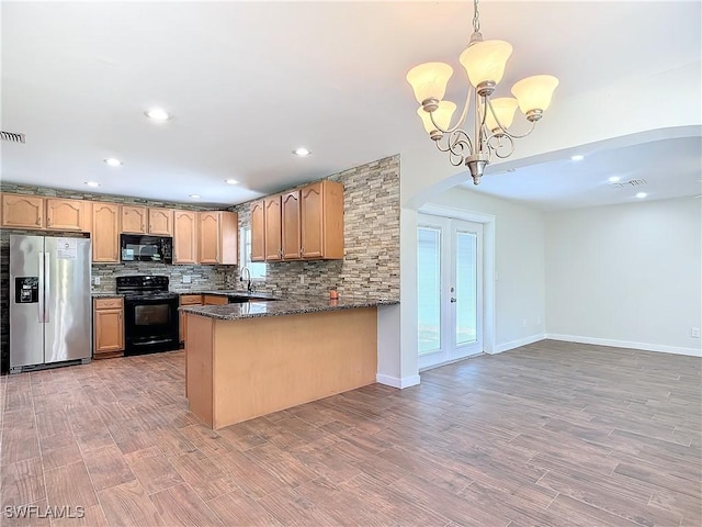 kitchen featuring black appliances, decorative light fixtures, dark stone countertops, backsplash, and kitchen peninsula