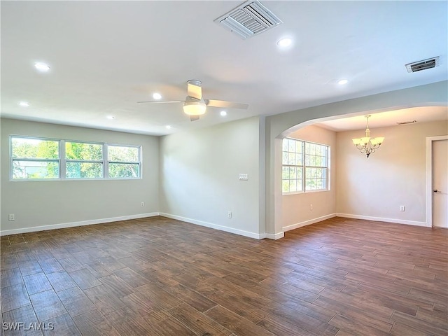 empty room with ceiling fan with notable chandelier and dark hardwood / wood-style flooring