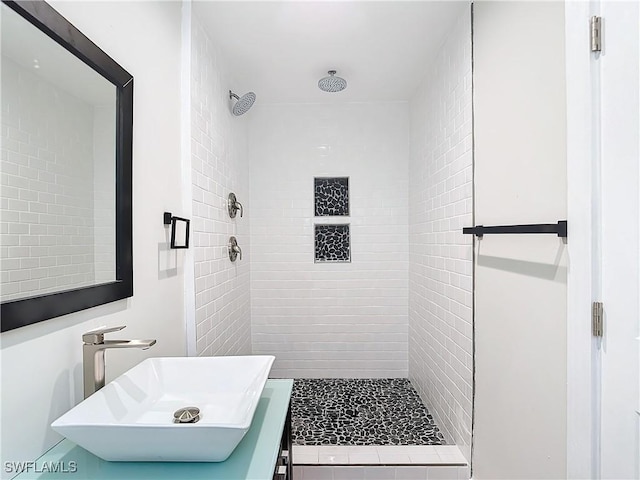 bathroom featuring tiled shower and sink