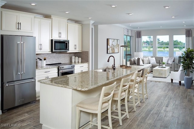 kitchen featuring white cabinetry, tasteful backsplash, high end appliances, sink, and a kitchen island with sink