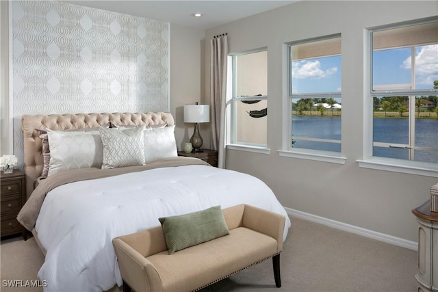 bedroom with light carpet and a water view