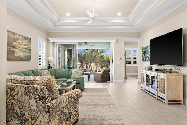 living room with ceiling fan, a tray ceiling, crown molding, and light hardwood / wood-style flooring