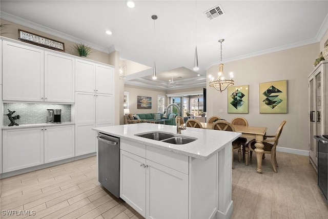 kitchen featuring pendant lighting, stainless steel dishwasher, sink, white cabinetry, and an island with sink