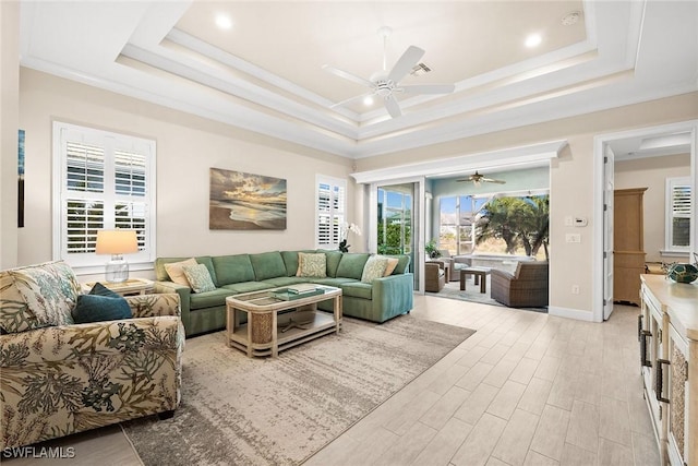 living room with ceiling fan, ornamental molding, and a tray ceiling