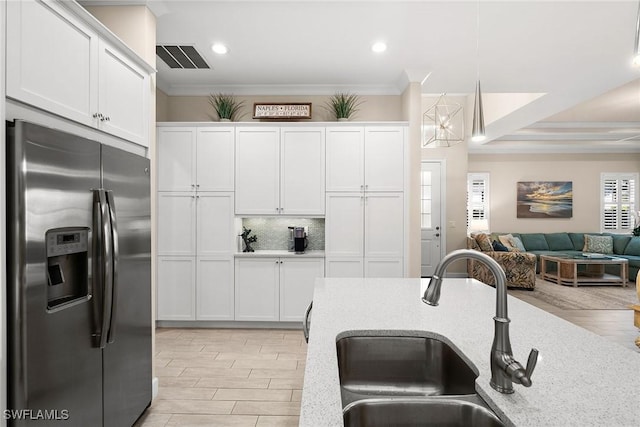 kitchen featuring sink, crown molding, white cabinetry, hanging light fixtures, and stainless steel fridge