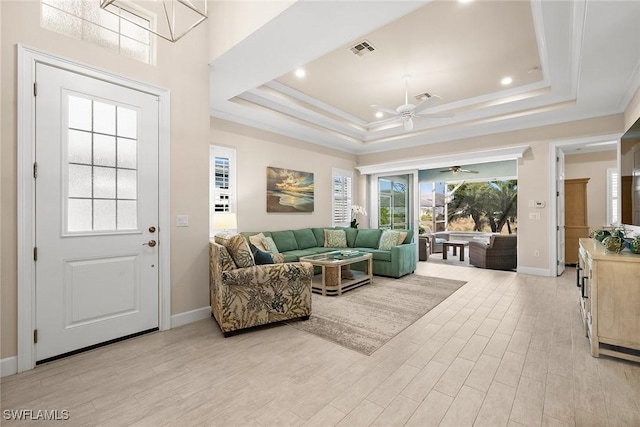 living room featuring ceiling fan, light hardwood / wood-style flooring, and a tray ceiling