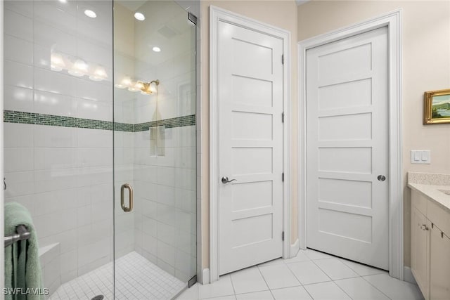 bathroom with a shower with door, tile patterned floors, and vanity