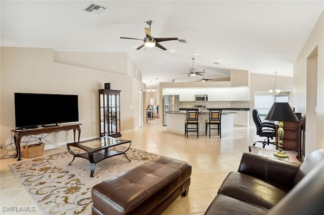 living room with ceiling fan with notable chandelier, light tile patterned flooring, and vaulted ceiling