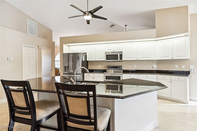 kitchen featuring ceiling fan, a kitchen island with sink, a breakfast bar area, stainless steel appliances, and white cabinets