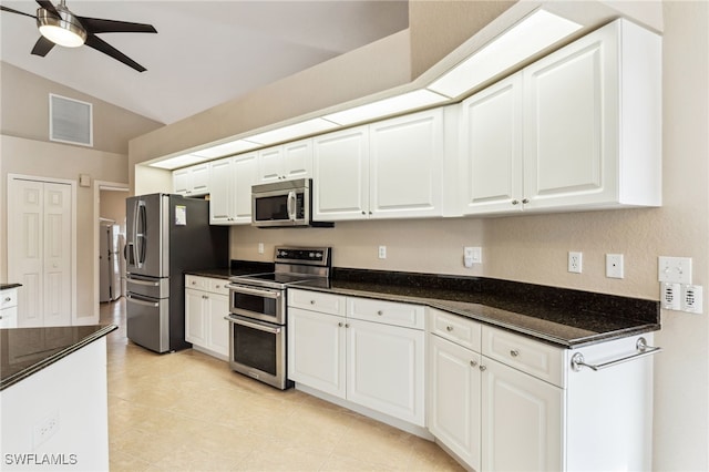 kitchen featuring white cabinets, vaulted ceiling, appliances with stainless steel finishes, and dark stone countertops