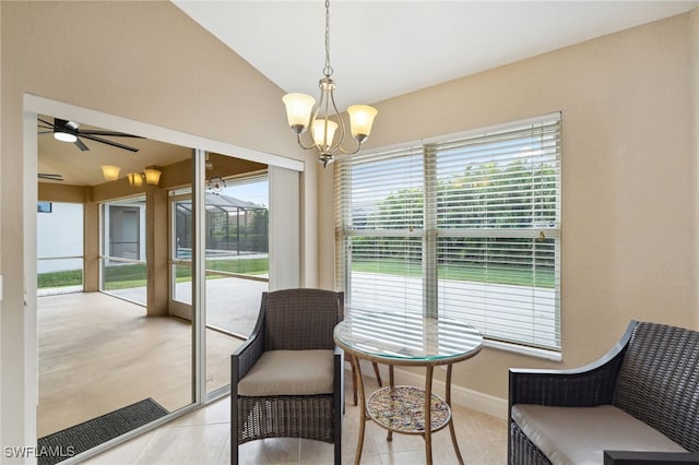 living area with ceiling fan with notable chandelier, vaulted ceiling, and light tile patterned flooring