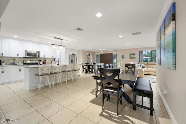 dining room featuring ornamental molding, sink, and light tile patterned floors