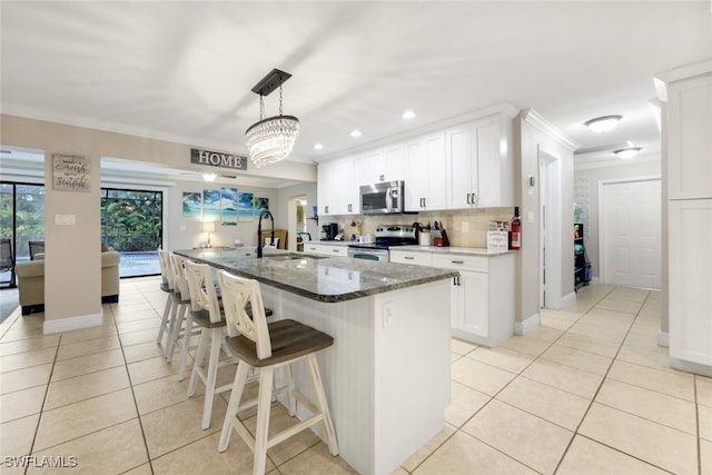 kitchen featuring appliances with stainless steel finishes, sink, white cabinets, decorative backsplash, and a kitchen island with sink