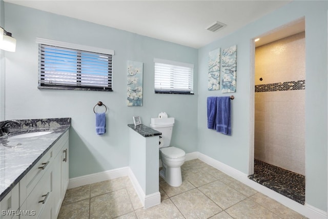 bathroom with tiled shower, vanity, toilet, and tile patterned floors