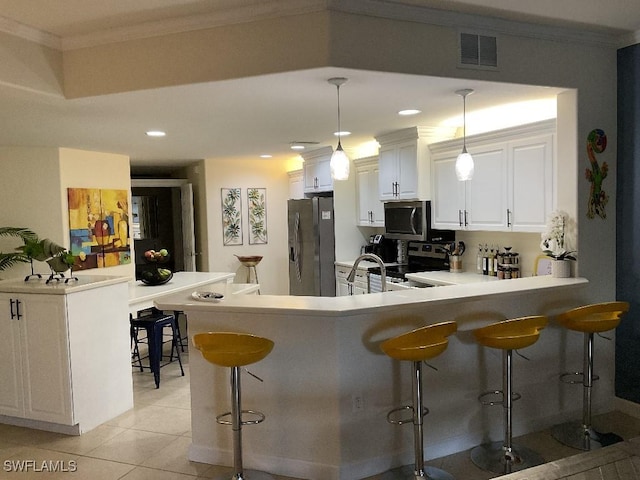 kitchen with pendant lighting, a breakfast bar, appliances with stainless steel finishes, white cabinets, and kitchen peninsula