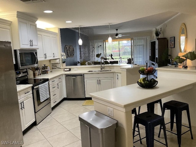 kitchen with sink, a breakfast bar, appliances with stainless steel finishes, white cabinetry, and kitchen peninsula