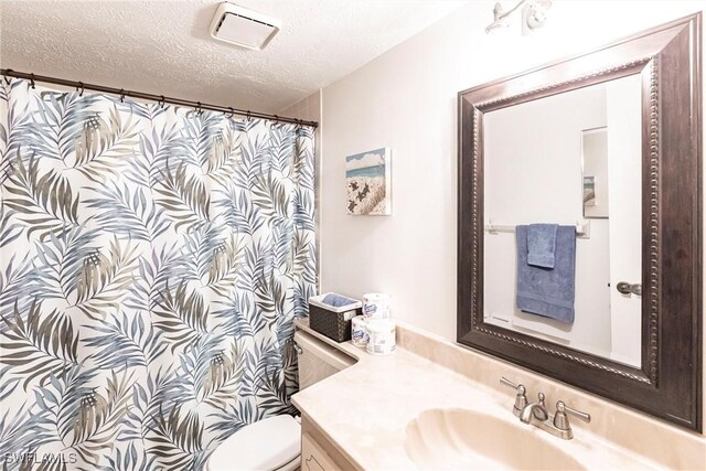 bathroom with vanity, a textured ceiling, and toilet