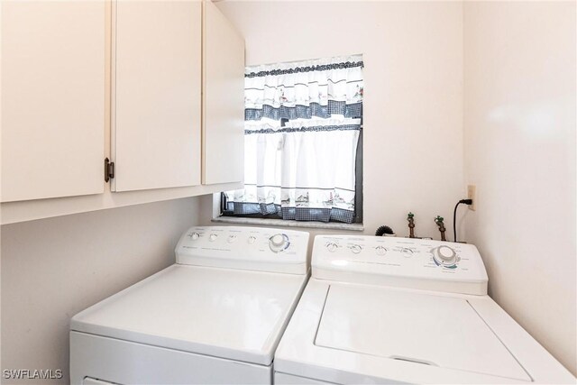 clothes washing area with washing machine and dryer and cabinets