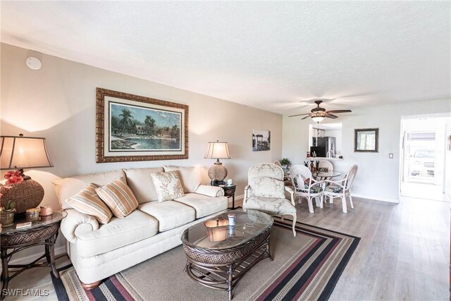 living room with ceiling fan, hardwood / wood-style flooring, and a textured ceiling