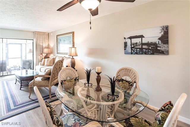 dining area with ceiling fan, wood-type flooring, and a textured ceiling