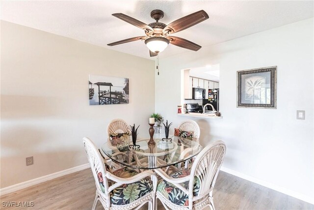 dining space with ceiling fan and light hardwood / wood-style floors