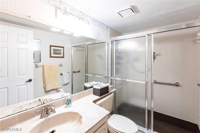 bathroom with vanity, walk in shower, a textured ceiling, and toilet