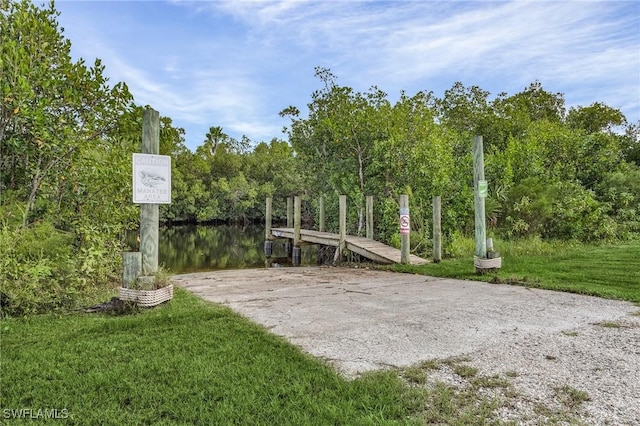 surrounding community featuring a water view, a lawn, and a dock