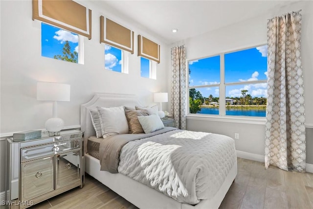 bedroom featuring light hardwood / wood-style flooring and a water view