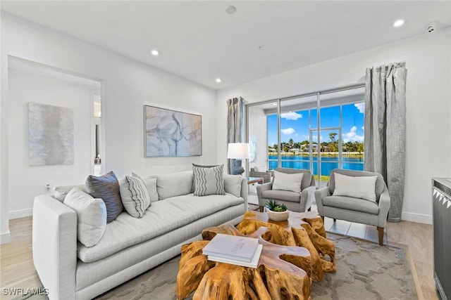 living room with light hardwood / wood-style floors and a water view