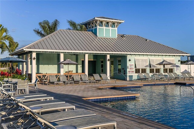 back of property featuring a community pool, a water view, and a patio