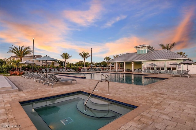 pool at dusk featuring a patio area and a community hot tub