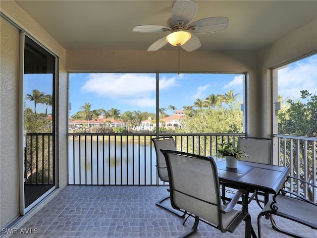 sunroom featuring a water view and ceiling fan