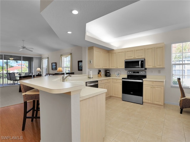 kitchen featuring sink, a breakfast bar, appliances with stainless steel finishes, a healthy amount of sunlight, and kitchen peninsula