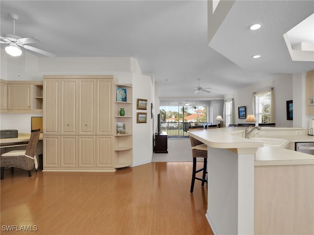 kitchen featuring a kitchen bar, built in desk, sink, and light hardwood / wood-style flooring