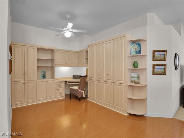 office space with built in desk, ceiling fan, and light hardwood / wood-style flooring