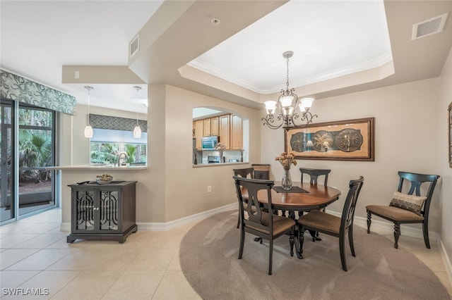 dining area featuring crown molding, an inviting chandelier, light tile patterned floors, and a tray ceiling