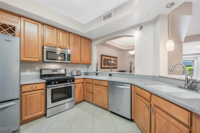 kitchen featuring appliances with stainless steel finishes, hanging light fixtures, sink, a raised ceiling, and ornamental molding