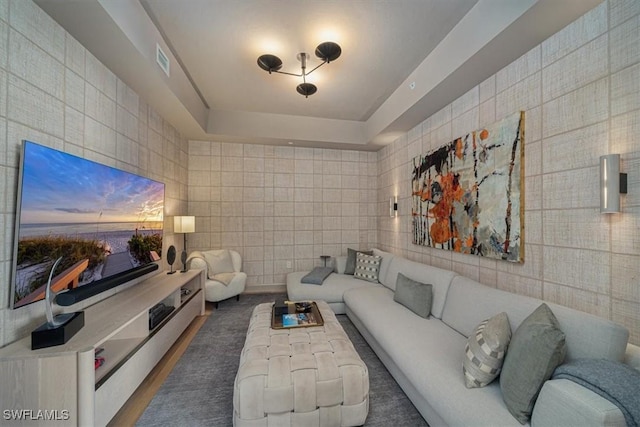 living room featuring tile walls and a raised ceiling