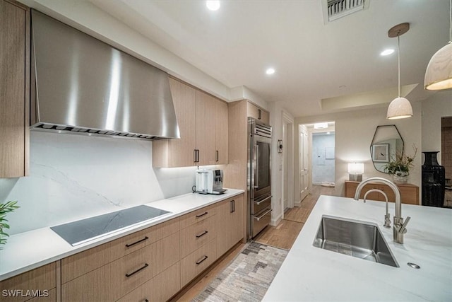 kitchen with extractor fan, black electric cooktop, pendant lighting, light hardwood / wood-style flooring, and sink