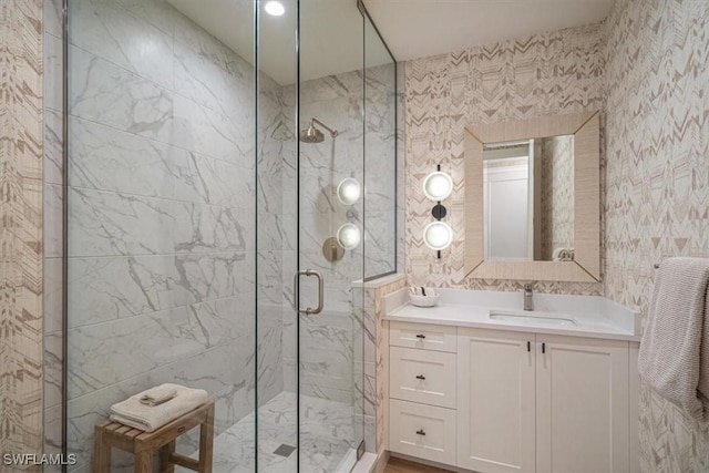 bathroom featuring a shower with door and vanity