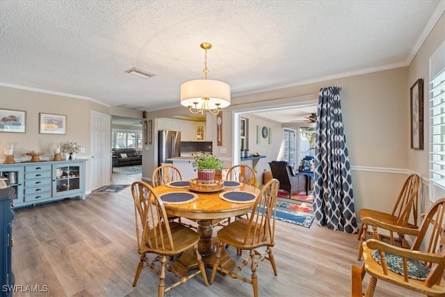 dining area with plenty of natural light, a textured ceiling, and light hardwood / wood-style flooring