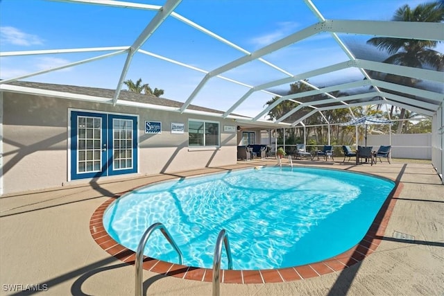 view of swimming pool featuring a patio, glass enclosure, and french doors