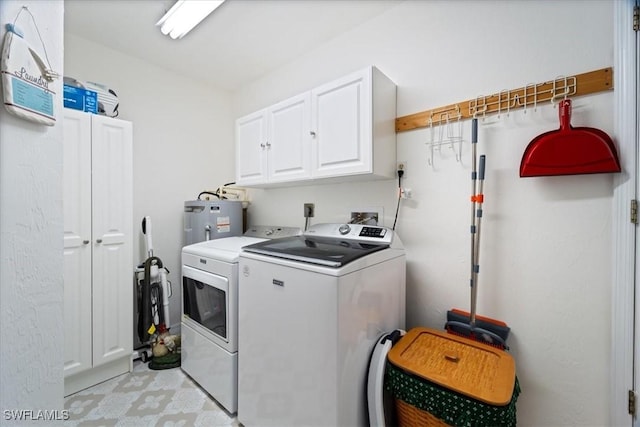 clothes washing area with cabinets, separate washer and dryer, and electric water heater