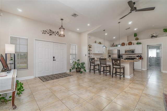 foyer entrance with ceiling fan and high vaulted ceiling