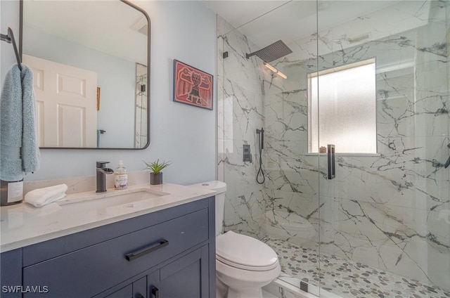 bathroom with toilet, vanity, and a shower with shower door