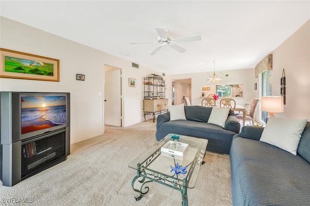 carpeted living room with ceiling fan with notable chandelier