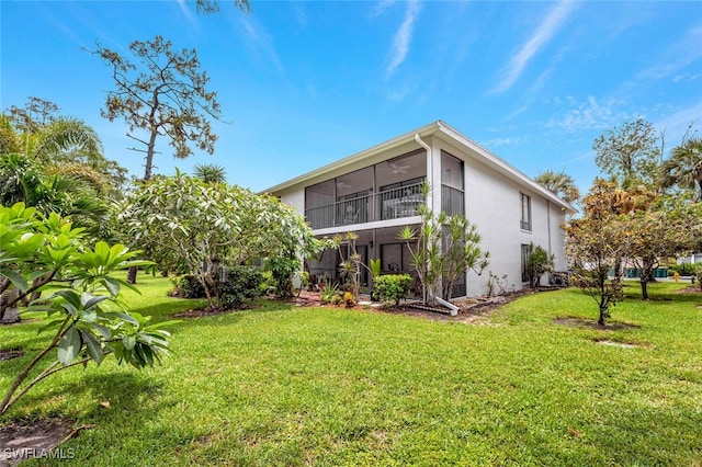 back of property with a sunroom and a lawn