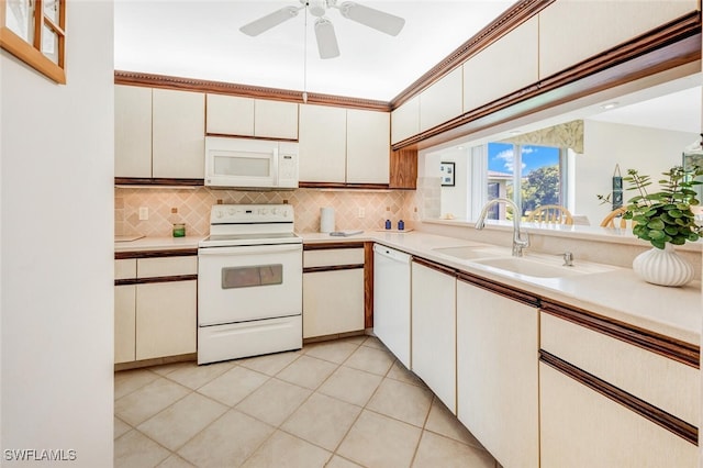 kitchen with light tile patterned floors, backsplash, white appliances, white cabinets, and sink