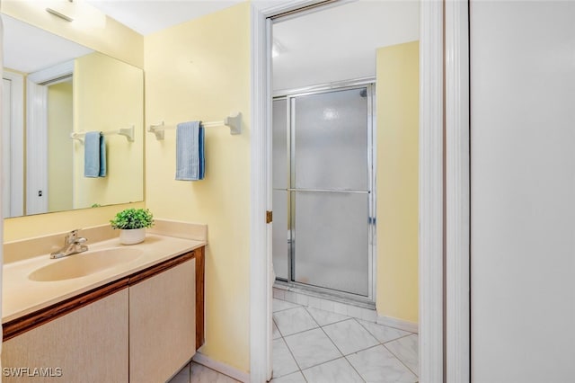 bathroom with a shower with shower door, vanity, and tile patterned floors